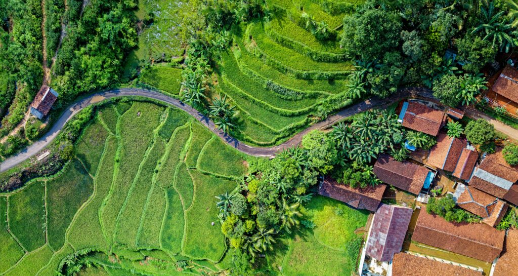 Stunning aerial view of lush rice terraces and rural village in Rumpin, Jawa Barat, Indonesia.